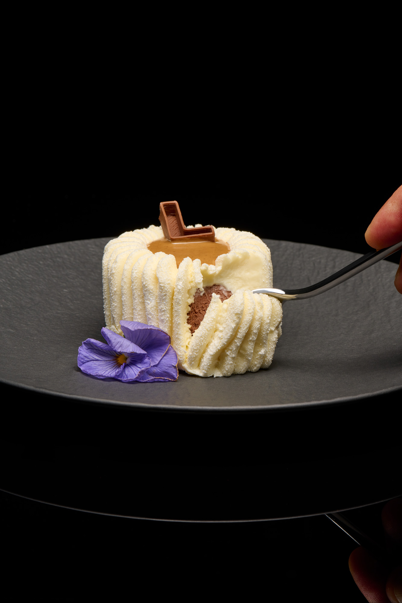 Dessert al cucchiaio con cuore al cioccolato aperto con la forchetta su fondo nero, fotografia di pasticceria