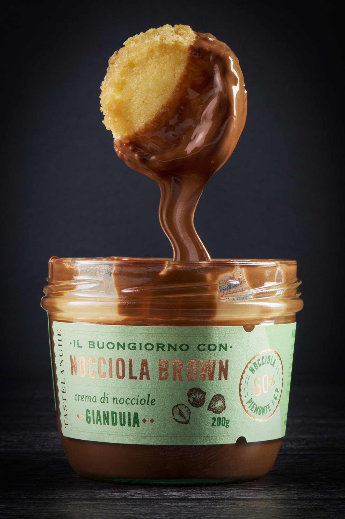Barattolo di crema di nocciole gianduia Tastelanghe con biscotto immerso e colata di crema, fotografia di packaging food